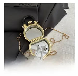 Mini gold acrylic box bag interior showing vanity mirrors and wireless earphone storage