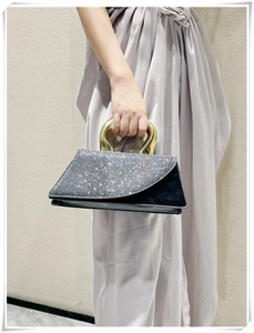 Close-up of a silver sequined evening bag with a unique gold metal handle detail