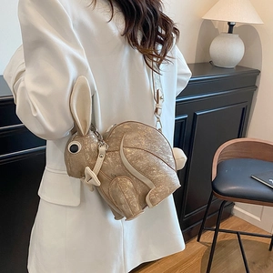 Champagne gold rabbit crossbody bag with metallic finish shown on model's shoulder