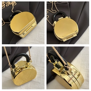 Detail view of mirror-finish gold mini box bag with black handle and gold metal chain