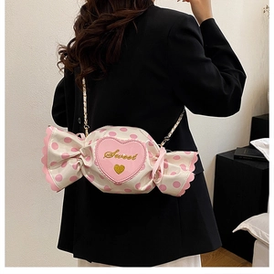 Detail of sweet candy-shaped bag with pink heart embroidery and gold chain strap