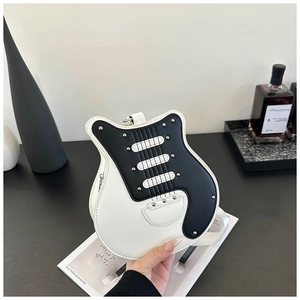 Detailed close-up of guitar-shaped crossbody bag with silver studs in a lifestyle setting