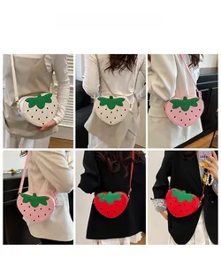 Détail des sacs bandoulière en forme de fraise en beige, rose et rouge portés par le mannequin