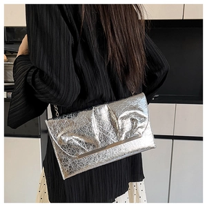 Sac bandoulière enveloppe argenté avec texture plissée métallique et chaîne dorée sur modèle