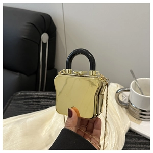 Detailed view of the toast-shaped glossy gold mini box bag with chain strap and top handle