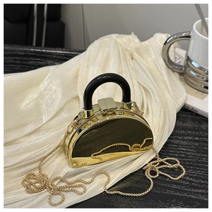 Detail of a mini semi-circle acrylic evening bag with glossy black finish and gold chain