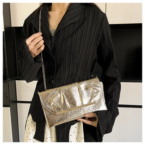 Détail de la pochette dorée texturée avec fine chaîne et finition en feuille plissée