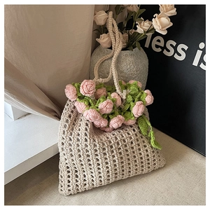 Detailed close-up of handmade pink crochet roses on a beige woven summer tote bag