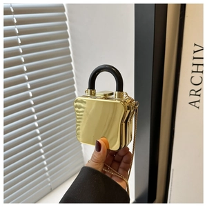 Detail of a mini mirror-finish gold toast-shaped bag with black handle and chain