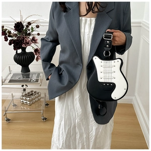 Detailed view of guitar-shaped crossbody bag with silver rivets worn by a model