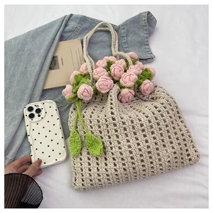 Detail showing pink crochet roses and green leaves on a beige woven bucket bag