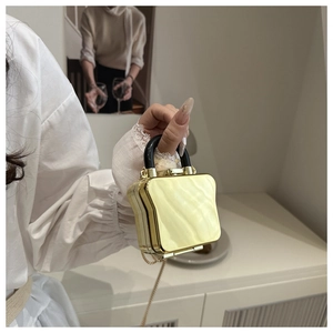 Detailed view of the mini toast-shaped handbag with golden mirror finish and chain