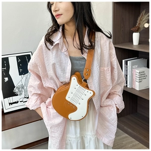 Detailed view of guitar shaped crossbody bag with brown and white rivets and wide strap