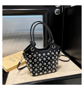 Detail view of fashion handbag featuring polished silver studs and cylindrical top handles