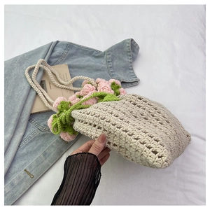 Detailed macro view of handmade crochet tote with pink floral accents and leaf designs