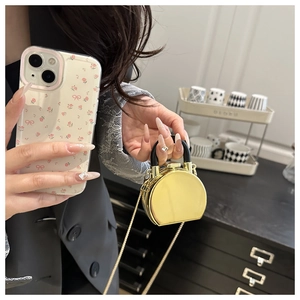 Detailed close-up of mini gold acrylic box bag with black handle and gold chain strap