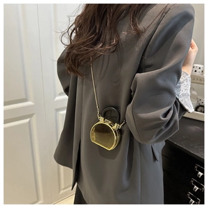 Detail of a shiny gold semi-circle mini bag with a black handle and chain strap