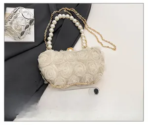 Detail of irregular wavy evening bag with cream 3D tulle roses and large pearl handle
