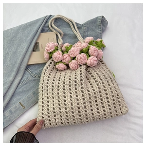 Close-up of woven tote bag featuring decorative pink 3D crochet roses and leaf details