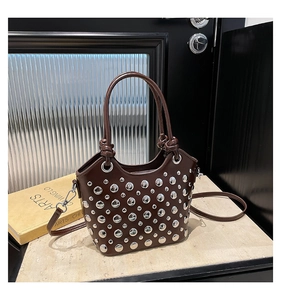 Detailed view of dark brown leather bucket bag with silver metal rivets and dual handles