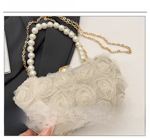 Detail of floral lace evening clutch with pearl handle and golden chain strap