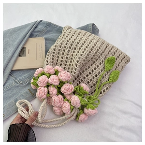 Detail of hand-woven beige tote bag featuring pink crochet roses and green leaf accents