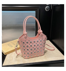 Detail shot of a pink bucket bag featuring silver round studs and dual handles with a strap