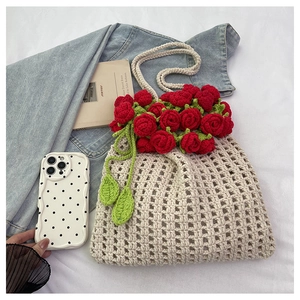 Detailed knit texture of crochet tote bag with vibrant 3D red roses and leaf charms