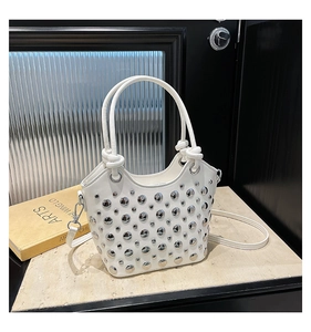 Detail view of white bucket bag featuring silver round metal rivets and detachable strap