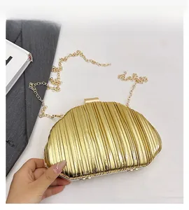 Detailed macro view of the gold pleated texture and metallic finish on the evening clutch bag