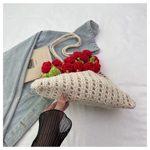 Close-up of beige crochet tote bag with red knitted 3D roses and leaves for summer style