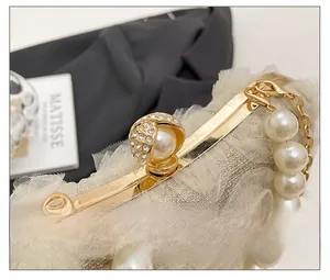Exquisite gold metal clasp with pearl inlay and lace detail on a luxury evening bag