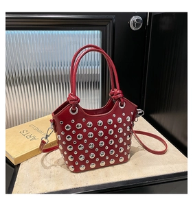 Detailed macro view of red bucket bag featuring shiny silver rivet studs and a top handle