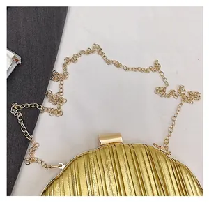 Close-up of golden shell evening clutch bag featuring vertical pleated texture and metal chain