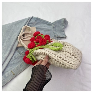 Detailed macro view of handmade crochet knit shoulder bag with red 3D roses and leaves
