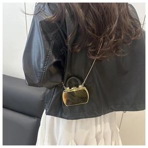 Close-up of a mini gold mirror acrylic box bag with a black handle and metal chain strap