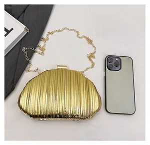 Detailed size comparison of gold pleated evening clutch bag showing phone storage space
