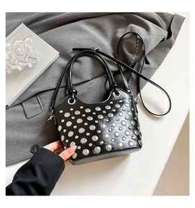 Detail of black glossy bucket bag featuring silver rivet studs and dual carry handles