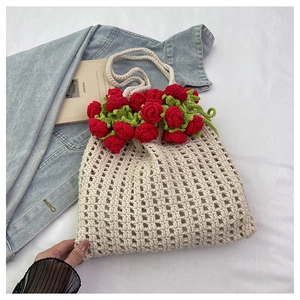 Close-up of handmade crochet bag featuring 3D red roses and green leaves decoration