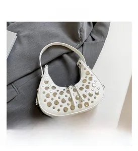 Detail view of white Hobo bag featuring polished silver stud accents on a grey fabric