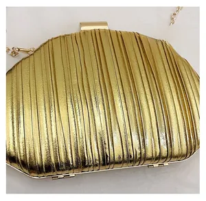 Close-up of gold pleated evening clutch bag with metallic texture and chain strap