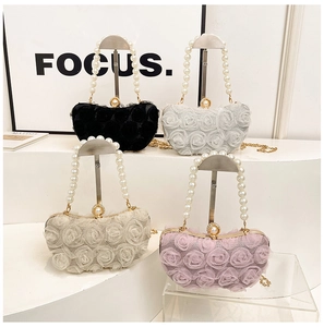Detail view of four elegant evening bags with 3D fabric flowers and pearl handles