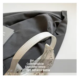 Close-up of a wide comfortable shoulder strap with silver rivet details on a white bucket bag