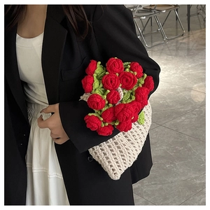 Detail of handmade crochet red rose bouquet with green leaves for summer shoulder bag