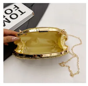 Detail view of the gold pleated evening clutch featuring chain strap and satin lining