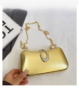 Close-up of golden evening clutch featuring brushed texture and diamond-encrusted buckle