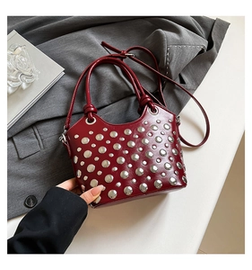 Close-up of wine red bucket bag with silver studs and adjustable shoulder strap