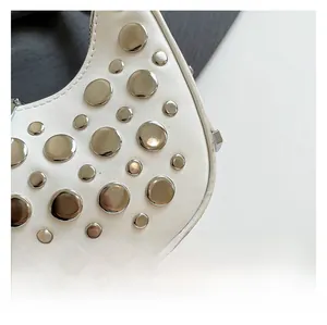 Detailed close-up of white leather crescent bag with silver metallic punk rivets