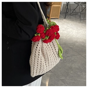 Close-up of handmade crochet shoulder bag featuring vibrant 3D red roses and green leaves