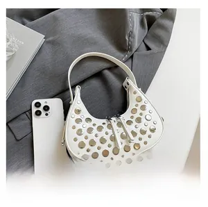 Detail of white half-moon bucket bag with silver metal studs on grey blazer